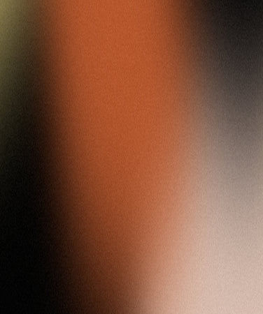 A blurred gradient image with dominant shades of orange, black, beige, and hints of yellow blending smoothly together.