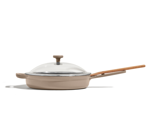 A beige nonstick frying pan with a long wooden handle and a clear glass lid, shown against a plain white background.