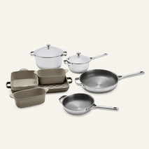 The Titanium Pro Cookware + Bakeware Set 2.0 includes stainless steel pots and pans with lids, alongside several rectangular, light brown ceramic bakeware dishes.