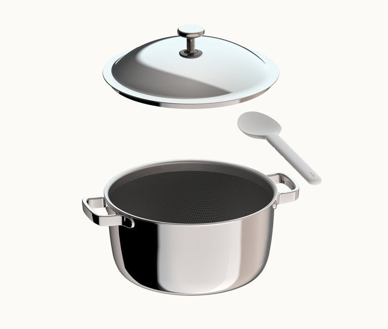 A stainless steel pot, its lid hovering above it, next to a white cooking spoon.