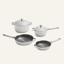 Titanium Pro Cookware Set 2.0 featuring two lidded stainless steel pots and two frying pans with silver handles and light gray exterior surfaces.
