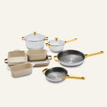 Titanium Pro Cookware + Bakeware Set 2.0 featuring high-performance metallic pots, pans, and ceramic bakeware with gold-toned handles and lids.